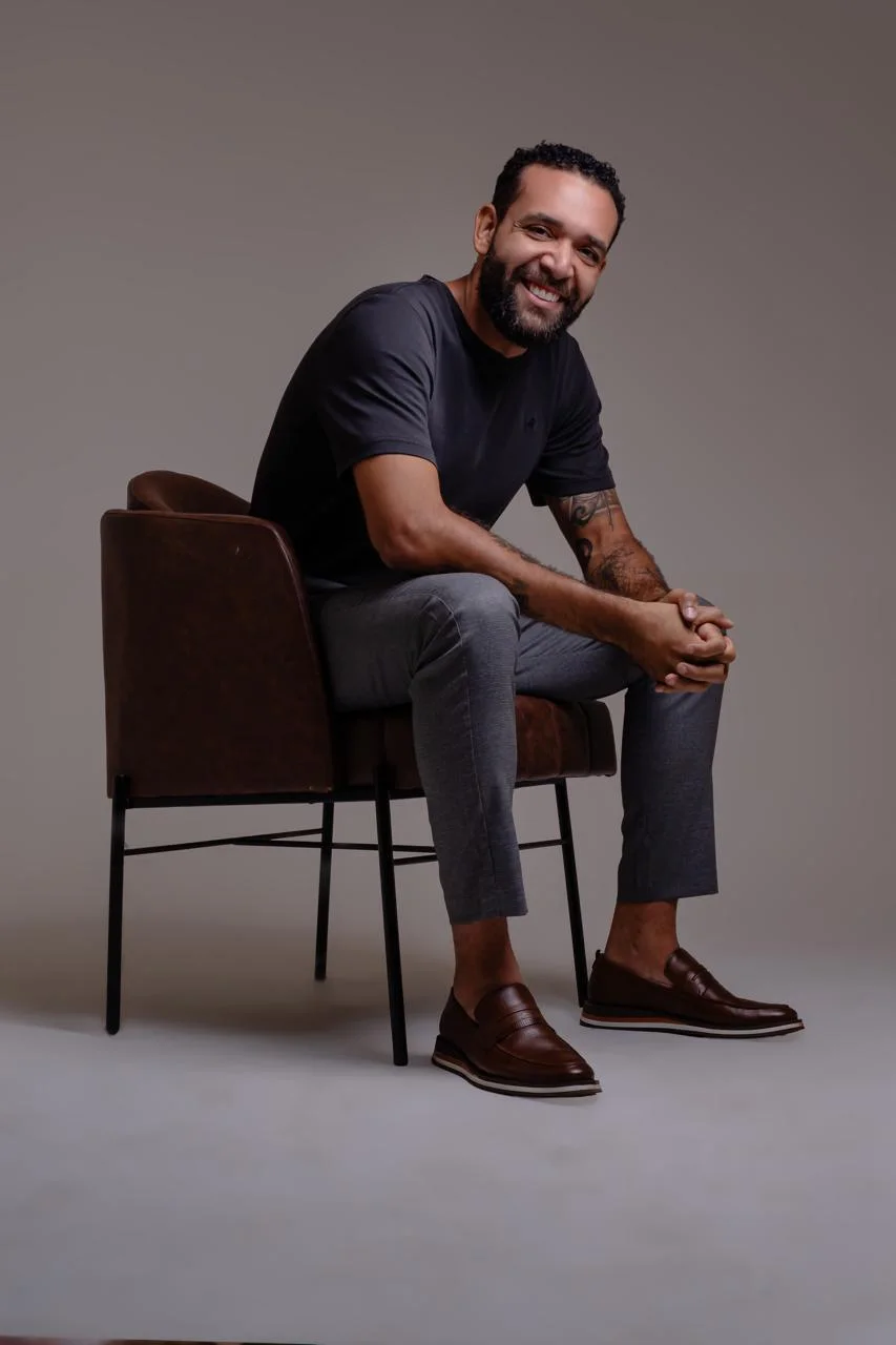 Marcelo Schmitsler sentado, sorrindo, em retrato de estúdio