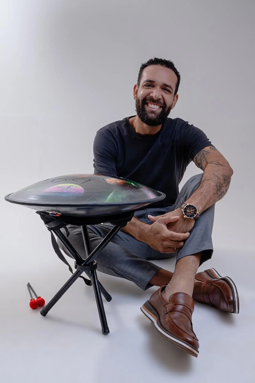 Marcelo Schmitsler sentado no chão com seu handpan, sorrindo