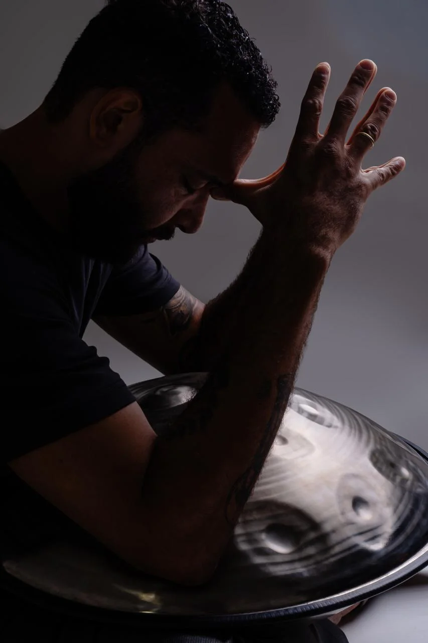 Marcelo Schmitsler em momento contemplativo com seu handpan, em contraluz