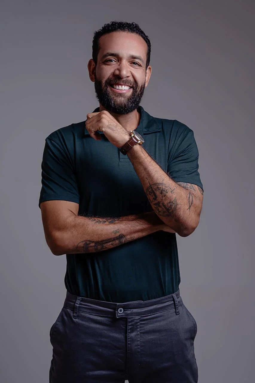 Marcelo Schmitsler sorrindo, com a mão no queixo, em retrato de estúdio